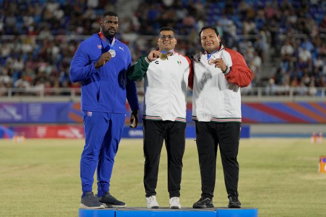Mexico's Jairo Moran (C), Cuba's Juan Vazquez (L) and Mexico's Uziel Munoz pose on the podium after winning the gold, silver and bronze medals, respectively, in the men's shot put final event during the XXV Central American and Caribbean Games at the Felix Sanchez Olympic Stadium in Santo Domingo on August 3, 2026. (Photo by Francesco SPOTORNO / AFP)