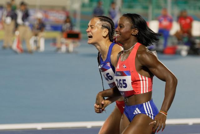 Dominican Republic's Liranyi Alonso (R) and Puerto Rico's Gladymar Torres react after winning the gold, and silver medals, respectively, in the women's 100m final during the XXV Central American and Caribbean Games at the Felix Sanchez Olympic Stadium in Santo Domingo on August 3, 2026. (Photo by Francesco SPOTORNO / AFP)