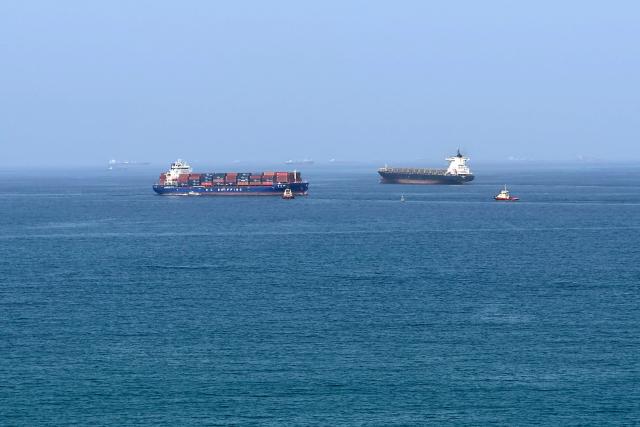 (FILES) A cargo ship is pictured off coast of the Khor Fakkan Container Terminal, the only natural deep-sea port in the region and one of the major container ports in Sharjah Emirate, along the Gulf of Oman on June 28, 2026. For 115 days, captain Mohammad Shafiqul Islam was stranded in the high seas of the Gulf, watching missiles light up the night sky and rationing food and water for his crew. "I tried to stay calm because I was responsible for 31 lives, a ship worth $40 million and cargo valued at $8.2 million," the 51-year-old Bangladeshi mariner told AFP, back home after the ordeal. (Photo by AFP) / 