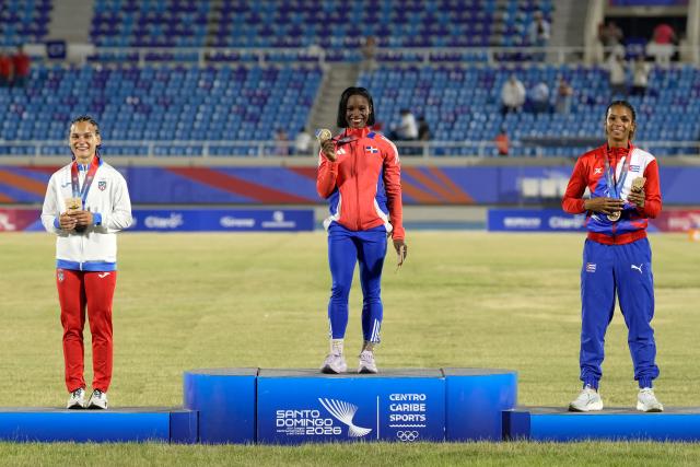 Dominican Republic's Liranyi Alonso (C), Puerto Rico's Gladymar Torres (L) and Cuba's Yarima Garcia pose on the podium after winning the gold, silver and bronze medals, respectively, in the women's 100m final during the XXV Central American and Caribbean Games at the Felix Sanchez Olympic Stadium in Santo Domingo on August 3, 2026. (Photo by Francesco SPOTORNO / AFP)