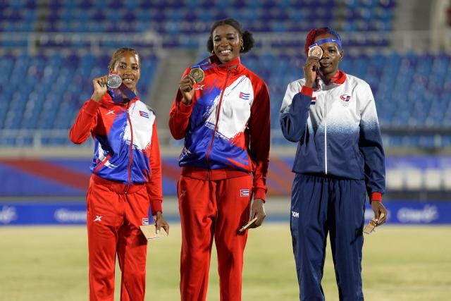 Cuba's Leyanis Perez (C), Cuba's Liadagmis Povea (L) and Dominican Republic's Ana Jose pose on the podium after winning the gold, silver and bronze medals, respectively, in the women's triple jump final during the XXV Central American and Caribbean Games at the Felix Sanchez Olympic Stadium in Santo Domingo on August 3, 2026. (Photo by Francesco SPOTORNO / AFP)