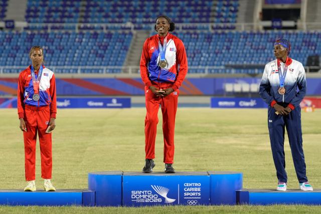 Cuba's Leyanis Perez (C), Cuba's Liadagmis Povea (L) and Dominican Republic's Ana Jose pose on the podium after winning the gold, silver and bronze medals, respectively, in the women's triple jump final during the XXV Central American and Caribbean Games at the Felix Sanchez Olympic Stadium in Santo Domingo on August 3, 2026. (Photo by Francesco SPOTORNO / AFP)