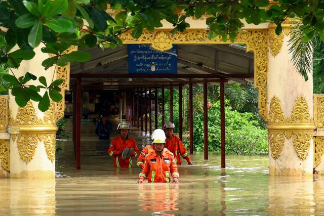 Rescuers and firefighters wade through waters at a flooded monastery in Lemyethna in Myanmar's Irrawaddy Delta region on August 3, 2026. (Photo by AFP)