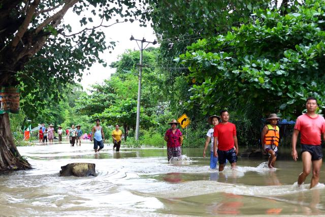 Residents walk along a flooded road in Lemyethna in Myanmar's Irrawaddy Delta region on August 3, 2026. (Photo by AFP)