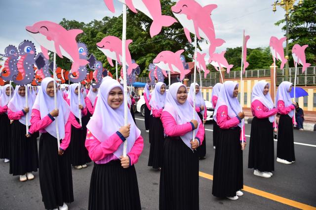 Students from Princess of Naradhiwas University hold dolphin and seahorse placards as they take part in the university's annual parade in southern Thailand's predominantly Muslim province of Narathiwat on August 4, 2026.  (Photo by Madaree TOHLALA / AFP)