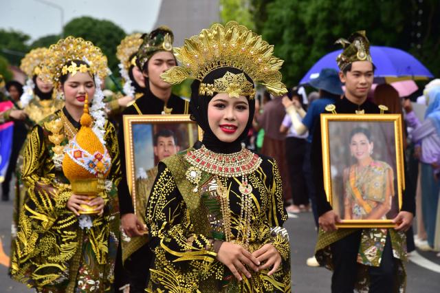 Students from Princess of Naradhiwas University take part in the university's annual parade, with participants holding portraits of Thailand's King Maha Vajiralongkorn and Thailand's Queen Suthida, in southern Thailand's predominantly Muslim province of Narathiwat on August 4, 2026.  (Photo by Madaree TOHLALA / AFP)