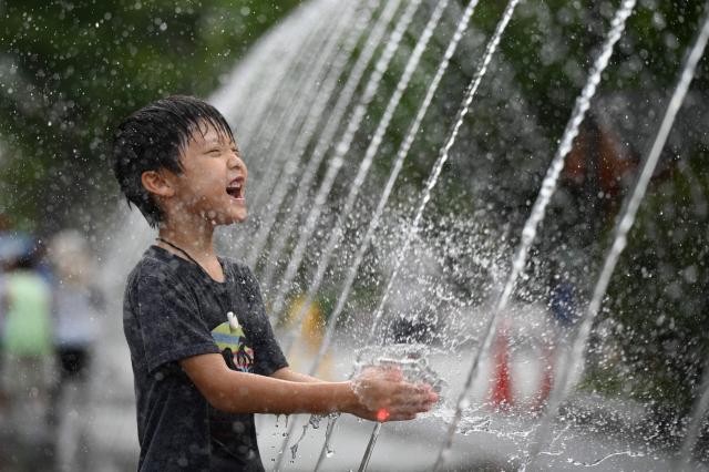 A child cools off in a fountain in Seoul on August 4, 2026. South Korea's summer heat has killed 16 people so far this year, the interior ministry said August 4, as the nation swelters in a wave of searing weather. (Photo by GREG BAKER / AFP)