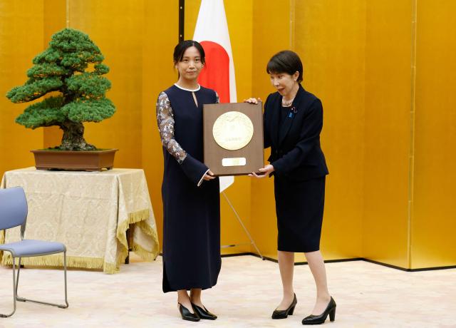 Japanese Prime Minister Sanae Takaichi (R) and speed skater Miho Takagi pose with the People's Honor Award plaque during a ceremony at the prime minister's office in Tokyo on August 4, 2026. (Photo by Franck ROBICHON / POOL / AFP)
