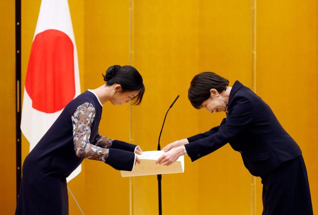 Japanese Prime Minister Sanae Takaichi (R) gives a certification of the People's Honor Award to speed skater Miho Takagi during a ceremony at the prime minister's office in Tokyo on August 4, 2026. (Photo by Franck ROBICHON / POOL / AFP)