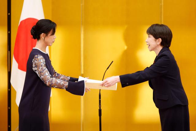 Japanese Prime Minister Sanae Takaichi (R) gives a certification of the People's Honor Award to speed skater Miho Takagi during a ceremony at the prime minister's office in Tokyo on August 4, 2026. (Photo by Franck ROBICHON / POOL / AFP)