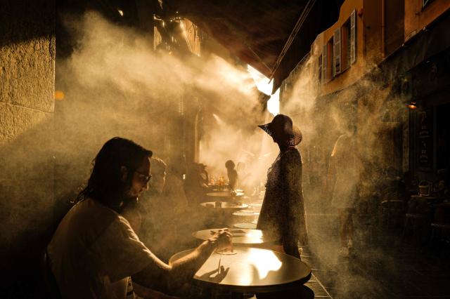 (FILES) People stand in front of a coffe shop during a heatwave in the French Riviera city of Nice on July 6, 2026. July 2026 was the hottest month ever recorded in France since records began in 1900, breaking the previous records set during the heatwaves of August 2003 and July 2006, Meteo-France announced on August 4, 2026. (Photo by Valery HACHE / AFP)