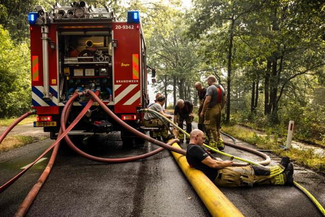 Firefighters take a break as they operate to extinguish a wildfire sweeping through the Boschhuizerbergen nature reserve near Oostrum, in the Dutch municipality of Venray, south-eastern Netherlands on August 4, 2026. (Photo by ROB ENGELAAR / ANP / AFP) / Netherlands OUT