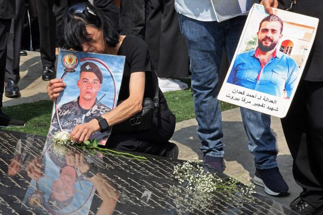 A woman lays a rose on the marble memorial engraved with the names of the victims of 2020 Beirut port blast near the blast's ground zero on the sixth anniversary of the explosion, in Beirut on August 4, 2026. The massive Beirut port explosion on August 4, 2020, killed more than 220 people, injured more that 6,500 and damaged swathes of the capital. Lebanese authorities have said the explosion was triggered by a fire in a warehouse where tonnes of ammonium nitrate fertiliser had been stored haphazardly for years, despite repeated warnings to senior officials. (Photo by Anwar AMRO / AFP)