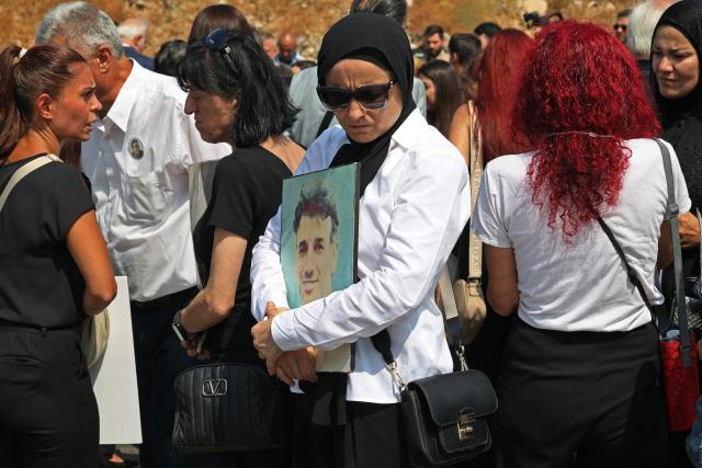 A family member carries the portrait of a victim of 2020 Beirut port blast near the blast's ground zero on the sixth anniversary of the explosion, in Beirut on August 4, 2026. The massive Beirut port explosion on August 4, 2020, killed more than 220 people, injured more that 6,500 and damaged swathes of the capital. Lebanese authorities have said the explosion was triggered by a fire in a warehouse where tonnes of ammonium nitrate fertiliser had been stored haphazardly for years, despite repeated warnings to senior officials. (Photo by Anwar AMRO / AFP)