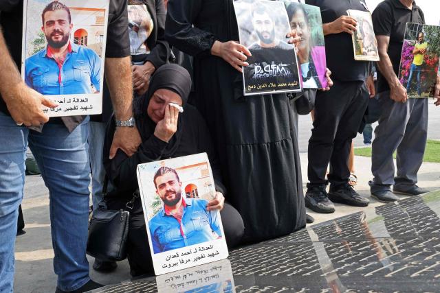 Family members carry the portraits of the victims of 2020 Beirut port blast as they gather around the marble memorial engraved with the names of the victims near the blast's ground zero on the sixth anniversary of the explosion, in Beirut on August 4, 2026. The massive Beirut port explosion on August 4, 2020, killed more than 220 people, injured more that 6,500 and damaged swathes of the capital. Lebanese authorities have said the explosion was triggered by a fire in a warehouse where tonnes of ammonium nitrate fertiliser had been stored haphazardly for years, despite repeated warnings to senior officials. (Photo by Anwar AMRO / AFP)