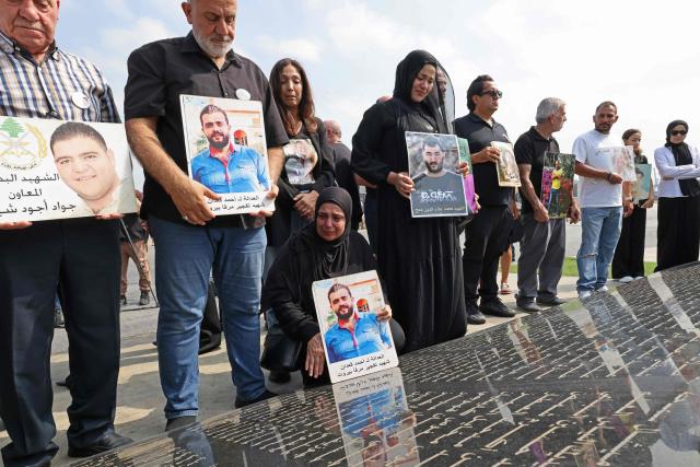 Family members carry the portraits of the victims of 2020 Beirut port blast as they gather around the marble memorial engraved with the names of the victims near the blast's ground zero on the sixth anniversary of the explosion, in Beirut on August 4, 2026. The massive Beirut port explosion on August 4, 2020, killed more than 220 people, injured more that 6,500 and damaged swathes of the capital. Lebanese authorities have said the explosion was triggered by a fire in a warehouse where tonnes of ammonium nitrate fertiliser had been stored haphazardly for years, despite repeated warnings to senior officials. (Photo by Anwar AMRO / AFP)