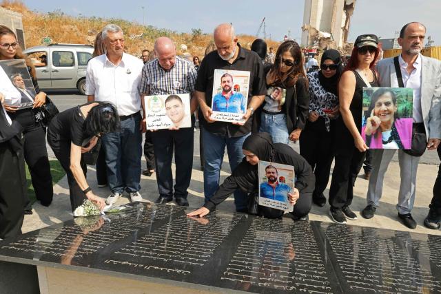 Family members carry the portraits of the victims of 2020 Beirut port blast as they gather around the marble memorial engraved with the names of the victims near the blast's ground zero on the sixth anniversary of the explosion, in Beirut on August 4, 2026. The massive Beirut port explosion on August 4, 2020, killed more than 220 people, injured more that 6,500 and damaged swathes of the capital. Lebanese authorities have said the explosion was triggered by a fire in a warehouse where tonnes of ammonium nitrate fertiliser had been stored haphazardly for years, despite repeated warnings to senior officials. (Photo by Anwar AMRO / AFP)