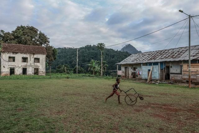 A boy runs throuh the playground of Sao Jose Sanzalas, the barracks or residential quarters built to house the forced laborers and workers at the Roca Sao Jose, near Santo Antonio, in Principe Island in Sao Tome and Principe, on August 3, 2026. Roca Sao Jose is a former colonial plantation (roca) situated on the island of Principe. It forms part of the rich heritage of the cocoa and coffee plantations in the archipelago of Sao Tome and Principe. (Photo by Daniel BELOUMOU OLOMO / AFP)