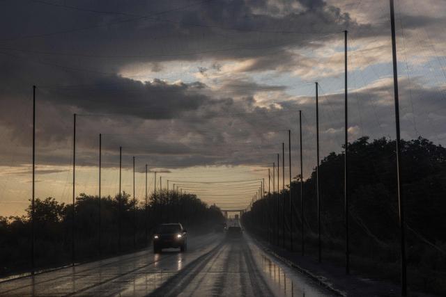 Cars drive along a road covered with anti-drone nets in the eastern Kharkiv region on July 29, 2026, amid the Russian invasion of Ukraine. (Photo by Roman PILIPEY / AFP)