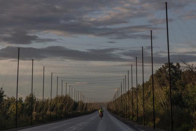 A motorcyclist rides along a road covered with anti-drone nets in the eastern Kharkiv region on July 29, 2026, amid the Russian invasion of Ukraine. (Photo by Roman PILIPEY / AFP)