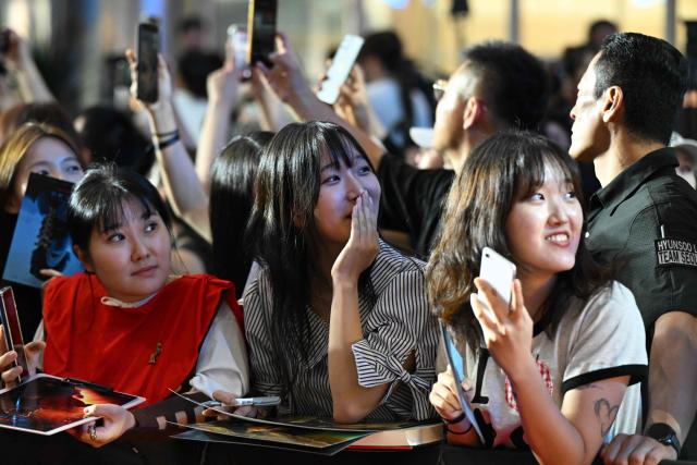 Fans look at a screen showing live coverage of the arrival of actors at a red carpet event for the film 'The Odyssey' in Seoul on August 4, 2026, ahead of its opening on August 5. (Photo by GREG BAKER / AFP)