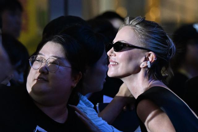 South African-US actress Charlize Theron poses with fans while signing autographs at a red carpet event for the film 'The Odyssey' in Seoul on August 4, 2026, ahead of its opening on August 5. (Photo by GREG BAKER / AFP)