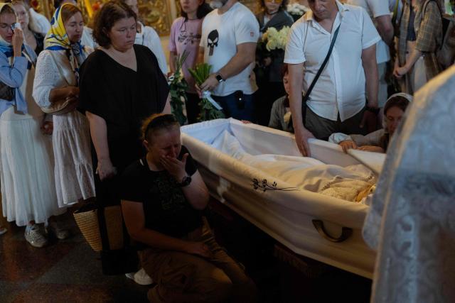Relatives and friends mourn at the coffin of Vitalina "Frau" Yarovenko, a 20-year-old volunteer and activist who was killed in a Russian attack that killed 9 people on August 1, during a funeral ceremony at the Saint Michael's Golden-Domed Monastery in Kyiv on August 4, 2026, amid the Russian invasion of Ukraine. (Photo by Tetiana DZHAFAROVA / AFP)