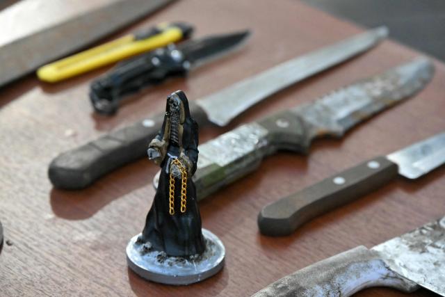 View of a statuette of the Holy Death and knives seized during a police operation near Las Cuadras Market in southern Quito, on August 4, 2026. The Ecuadorian government deployed on August 3, 2026, 4,000 police officers and military personnel in Quito to step up security in the capital, following the discovery of a decapitated body and reports of people going missing in recent weeks. (Photo by Rodrigo BUENDIA / AFP)