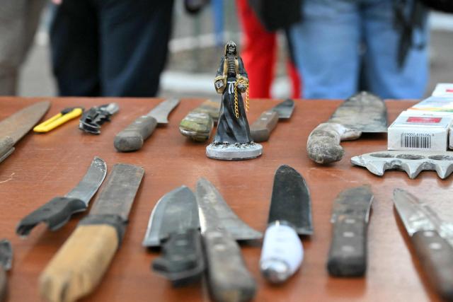 View of a statuette of the Holy Death and knives seized during a police operation near Las Cuadras Market in southern Quito, on August 4, 2026. The Ecuadorian government deployed on August 3, 2026, 4,000 police officers and military personnel in Quito to step up security in the capital, following the discovery of a decapitated body and reports of people going missing in recent weeks. (Photo by Rodrigo BUENDIA / AFP)