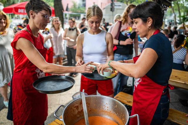 Elif Eralp (R), The Left Party's (Die Linke) main candidate in upcoming regional elections in Berlin serves Gazpacho at a cafe during a campaign stop in Berlin's Schoeneberg district on August 4, 2026. Berlin goes to the polls on September 20, 2026. (Photo by John MACDOUGALL / AFP)