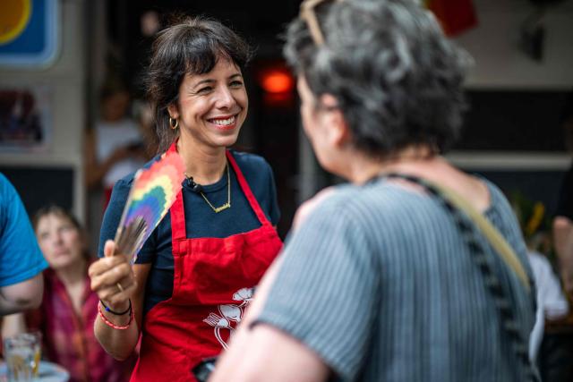 The Left Party's (Die Linke) main candidate in upcoming regional elections in Berlin Elif Eralp (L) interacts with a resident at a cafe during a campaign stop in Berlin's Schoeneberg district on August 4, 2026. Berlin goes to the polls on September 20, 2026. (Photo by John MACDOUGALL / AFP)