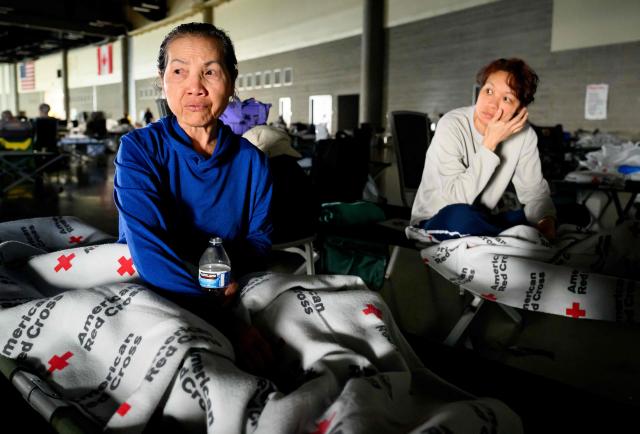 A woman and her daughter wait for news on the status of their home at a Red Cross evacuation center in Spokane, Washington, on August 4, 2026. US authorities arrested a man on August 3, 2026 on suspicion of arson in connection with the biggest of three fires burning around the northwestern city of Spokane, as firefighters raced to contain flames that have displaced tens of thousands. Wildfires supercharged by drought and intense heat have torn through the city in Washington state, burning thousands of acres and reducing hundreds of buildings to cinders while anxious families await news on when they can return. (Photo by Josh Edelson / AFP)