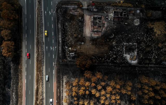 This aerial photograph shows cars driving down a road next to burnt properties in the wake of a wildfire that swept through the Gironde region in Lanton, along the Arcachon bay, southwestern France on August 4, 2026. (Photo by Christophe ARCHAMBAULT / AFP)