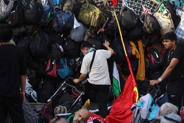 A Sia Muslim pilgrim checks his bag hanging on a fence outside the Imam al-Abbas Shrine in the holy city of Karbala, south of Baghdad on August 4, 2026, during the Arbaeen pilgrimage, which commemorates 40 days of mourning after the killing of Imam Hussein, the grandson of the Prophet Mohamed, at the 7th-century battle of Karbala. Arbaeen, one the world's largest annual public gathering, marks one of the most significant events in the Shia Muslim calendar, during which pilgrims from various countries visit the holy shrines. (Photo by AHMAD AL-RUBAYE / AFP)