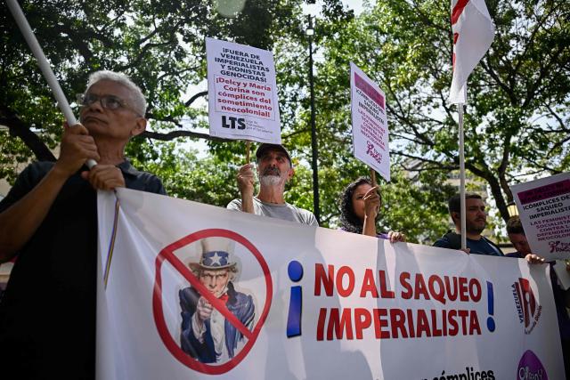 Members of the Communist Party of Venezuela (PCV) hold a banner that reads in Spanish "No to imperialist looting" during a protest against US interference in Venezuela at El Venezolano Square in Caracas on August 4, 2026. (Photo by Federico PARRA / AFP)
