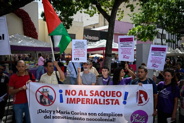 Members of the Communist Party of Venezuela (PCV) hold a banner that reads in Spanish "No to imperialist looting" during a protest against US interference in Venezuela at El Venezolano Square in Caracas on August 4, 2026. (Photo by Federico PARRA / AFP)