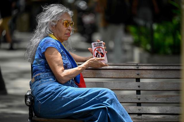 A woman holds flyers depicting US symbol Uncle Sam during a protest against US interference in Venezuela at El Venezolano Square in Caracas on August 4, 2026. (Photo by Federico PARRA / AFP)