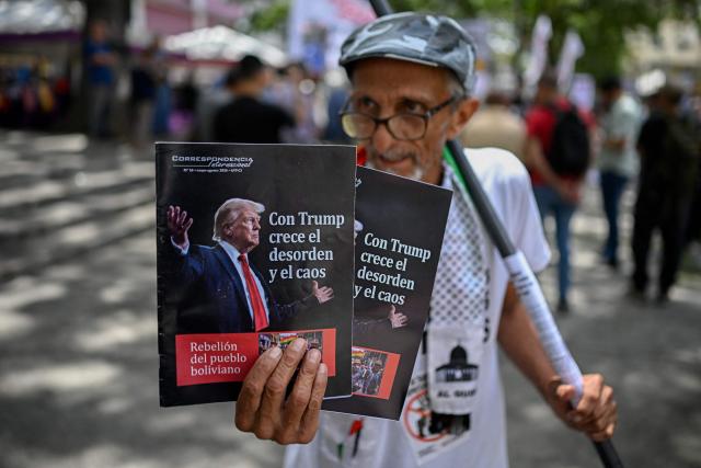 A man shows signs depicting US President Donald Trump during a protest against US interference in Venezuela at El Venezolano Square in Caracas on August 4, 2026. (Photo by Federico PARRA / AFP)