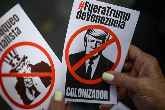 A woman holds flyers depicting US President Donald Trump and symbol Uncle Sam during a protest against US interference in Venezuela at El Venezolano Square in Caracas on August 4, 2026. (Photo by Federico PARRA / AFP)