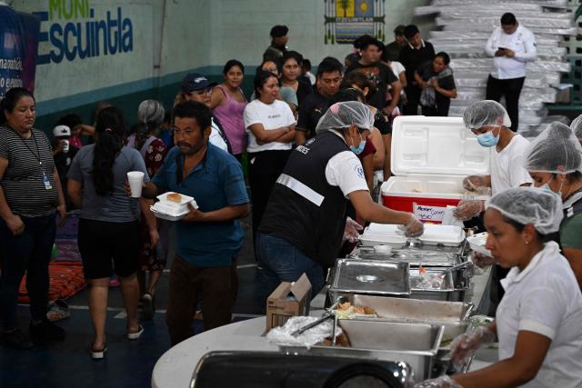 Evacuees receive food at a shelter after fleeing their village following the eruption of Fuego volcano in Escuintla, Guatemala, on August 4, 2026. Guatemalan authorities issued the country's second-highest emergency alert level on August 4 after a major eruption of Central America's most active volcano, prompting the evacuation of nearby villages. (Photo by Johan ORDONEZ / AFP)