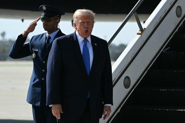 US President Donald Trump reacts after stepping off Air Force One upon arrival at Los Angeles International Airport in Los Angeles on August 4, 2026. US President Donald Trump will stop at his Trump National Golf Club Los Angeles before departing for Las Vegas, where he is expected to deliver remarks on August 5 at Red Rock Casino Resort & Spa in Summerlin, Nevada, promoting the administration's tax-cut policies, including the "no tax on tips" measure. (Photo by Jim WATSON / AFP)
