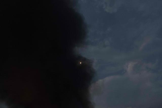 This photograph shows the moon as smoke rises from a warehouse destroyed in massive Russian ballistic missile and drone strikes on the outskirts of Kyiv on August 5, 2026, amid the Russian invasion of Ukraine. Russian strikes on Ukraine's capital and surrounding region killed at least two people and wounded dozens more, authorities said on August 5, 2026, after fresh overnight missile and drone attacks. (Photo by Roman PILIPEY / AFP)