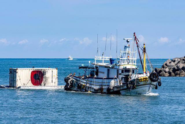 A chartered fishing vessel tows a modified container target barge showing bullet mark damage during naval training manoeuvres on the first day of the Han Kuang military exercise off Kaohsiung on August 5, 2026. (Photo by cheng-chia huang / AFP)