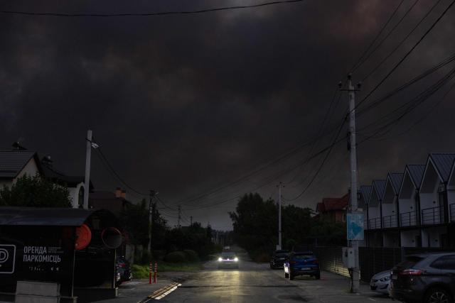 A car drives as smoke rises over residential buildings following massive Russian ballistic missile and drone strikes on the outskirts of Kyiv early on August 5, 2026, amid the Russian invasion of Ukraine. Russian strikes on Ukraine's capital and surrounding region killed at least two people and wounded dozens more, authorities said on August 5, 2026, after fresh overnight missile and drone attacks. (Photo by Roman PILIPEY / AFP)