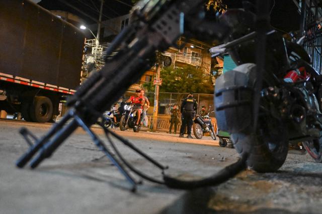 Colombian policemen and solldiers stand guard as people transit in the Melendez neighborhood prior to the upcoming presidential inauguration of Colombia's president-elect Abelardo de la Espriella, in Cali, Colombia, on August 4, 2026. De la Espriella's inauguration will take place on August 7, 2026. (Photo by JOAQUIN SARMIENTO / AFP)