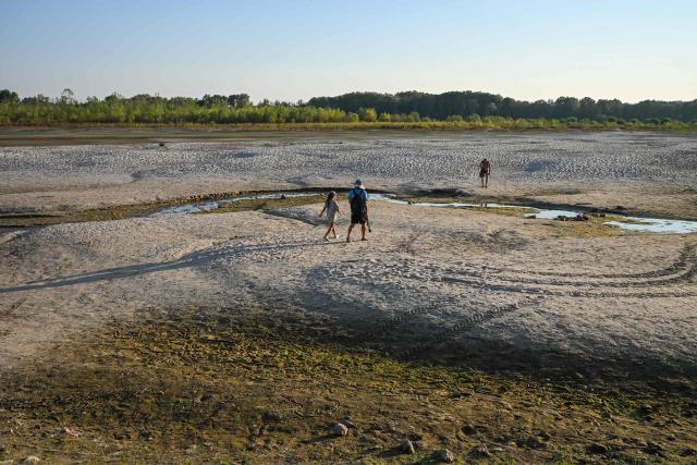 People walk across sandbars exposed by the low water level of the Danube River near Apatin, Serbia, on August 4, 2026, as prolonged hot and dry weather continues to lower water levels across the country. Scientists say global warming is increasing droughts and causing weather emergencies to become more extreme and more frequent. Prolonged drought and hot weather across Europe have pushed water levels along the Danube river to record seasonal lows, reaching its lowest flow rate in the last 30 years. (Photo by Nenad MIHAJLOVIC / AFP)