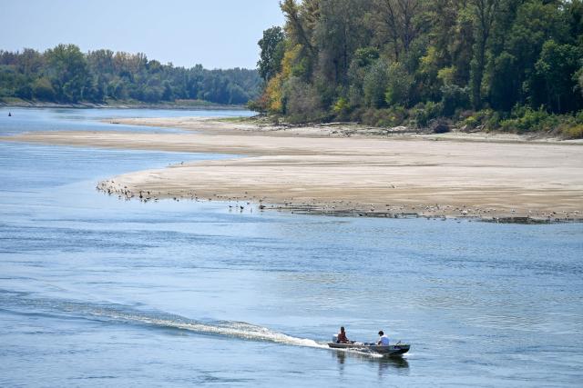 People in a small boat navigate past sandbars exposed by the low water level of the Danube River near Apatin, Serbia, on August 4, 2026, as prolonged hot and dry weather continues to lower water levels across the country, hampering navigation along the river. Scientists say global warming is increasing droughts and causing weather emergencies to become more extreme and more frequent. Prolonged drought and hot weather across Europe have pushed water levels along the Danube river to record seasonal lows, reaching its lowest flow rate in the last 30 years. (Photo by Nenad MIHAJLOVIC / AFP)