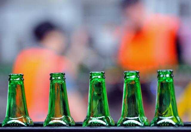 (FILES) A view of Heineken beer bottles on a conveyor belt at the Heineken brewery in Mons-en-Baroeul, run by the Heineken France group, on April 2, 2014. Heineken reported on August 5, 2026, that profits grew in the first half of the year, as the world's second-largest brewer pursues a restructuring plan that includes the arrival of a new chief executive in October. Net profit rose 10.2 percent on like-for-like comparisons that strip out the impacts of acquisitions or sales, to 1.26 billion euros ($1.45 billion). (Photo by Philippe HUGUEN / AFP)