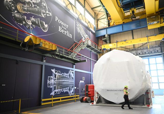 (FILES) An employee walks by a covered gas turbine at the Siemens Energy plant, part of German industrial conglomerate Siemens in Berlin on August 28, 2024, during a one-day-visit of the British Prime Minister to the German capital. German turbine-maker Siemens Energy said on AUGUST 5, 2026 that its core profit had tripled as the company gains from surging electricity demand driven by the AI boom. (Photo by Justin TALLIS / POOL / AFP)