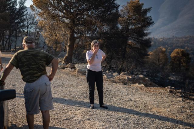 A local resident reacts as she looks at the area affected by a wildfire in Porto Germeno, some 70 kilometres (45 miles) northwest of Athens, on August 5, 2026. Greek officials and residents of a region west of the capital Athens on August 5, 2026, began to assess the damage suffered by homes, businesses and farmland scorched by a wildfire. (Photo by Angelos TZORTZINIS / AFP)